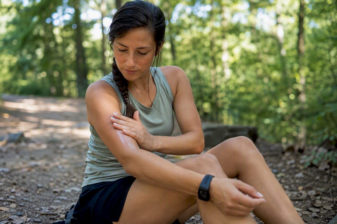 Runner applying natural balm repellent on arm